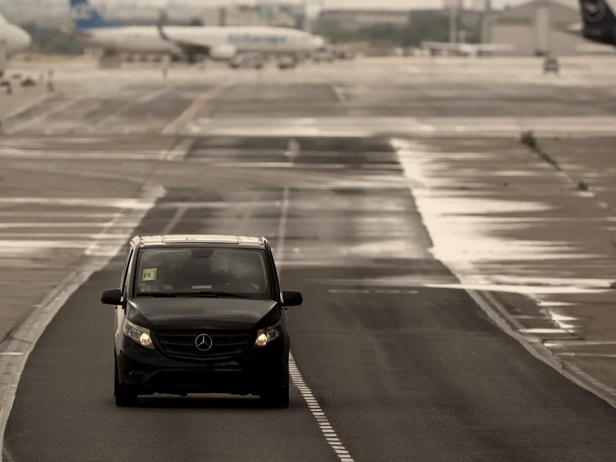 Black transit van moving along an open wet corridor with motion blur