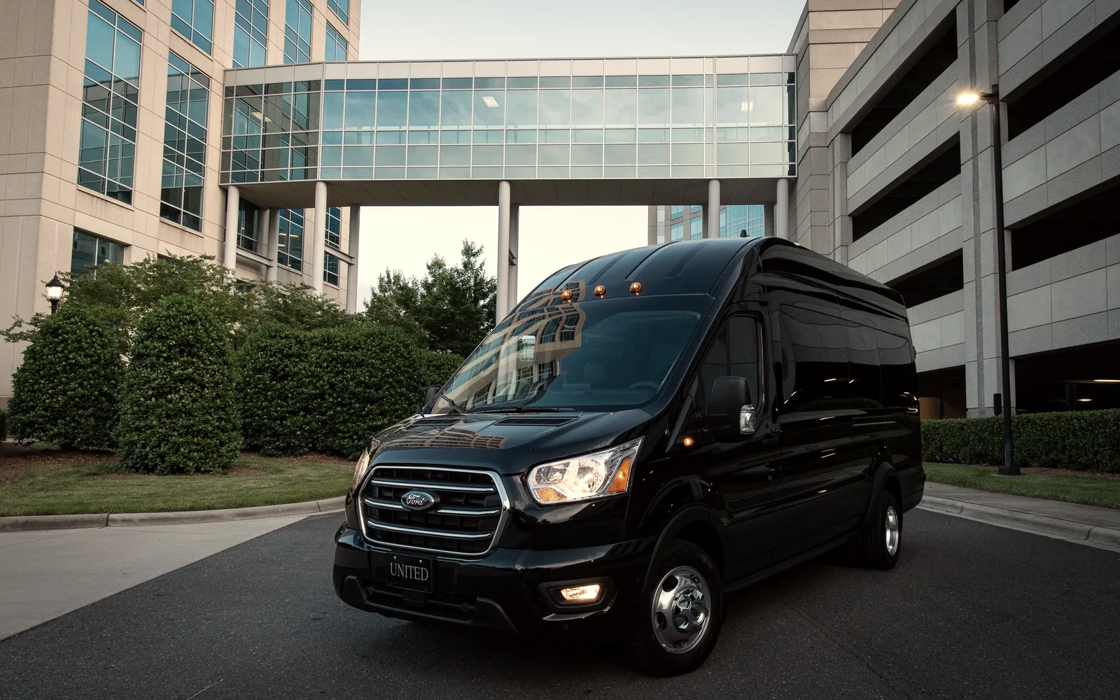 Dark high roof transit van in three quarter view against a modern concrete and glass building