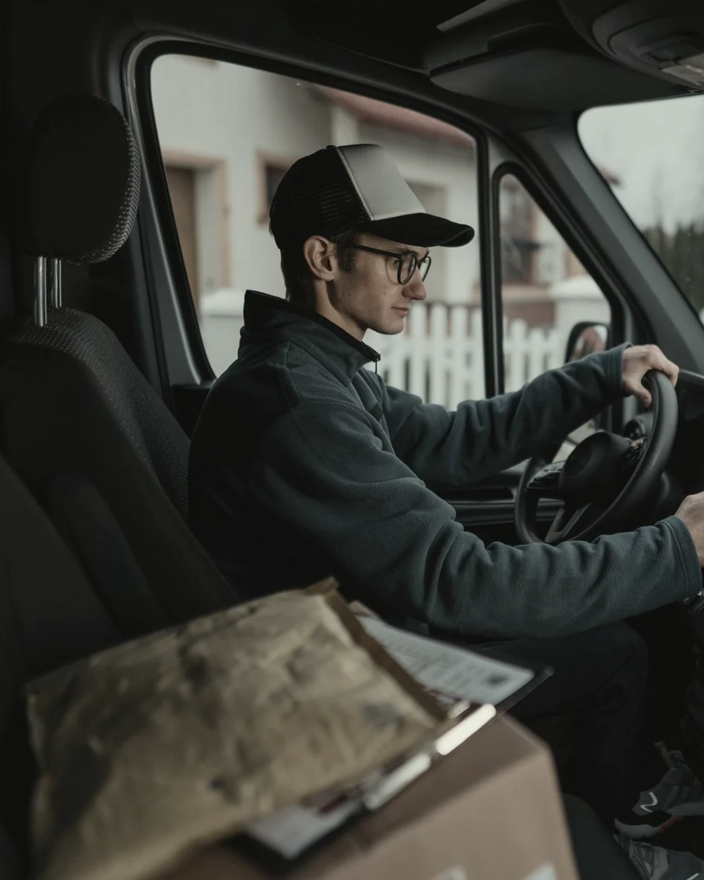 Courier at the wheel of a delivery van with a parcel on the dashboard and navigation running