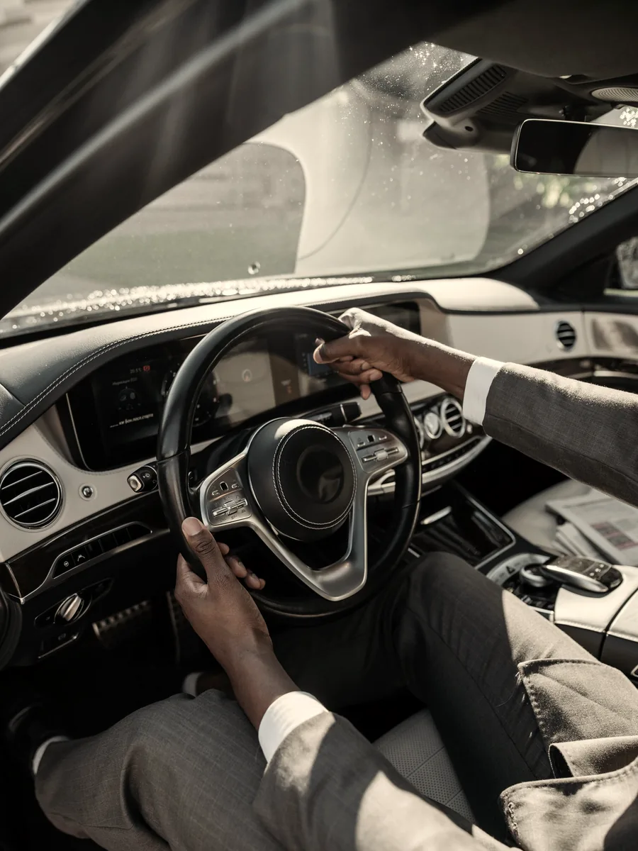 Suited operator with both hands on the steering wheel of a luxury cabin